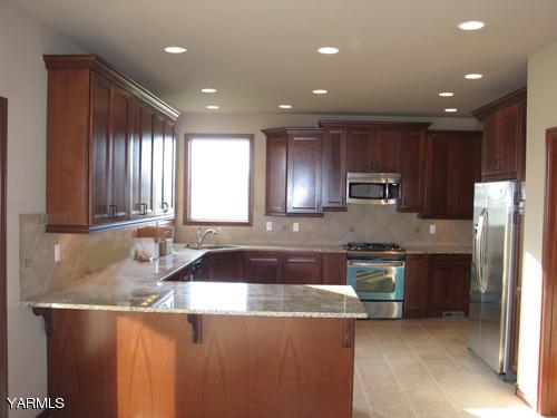 8990 Coolidge Road, Unit 7 Yakima, WA 98903 - Photo 4 of 15 a kitchen with kitchen island granite countertop wooden cabinets and a sink