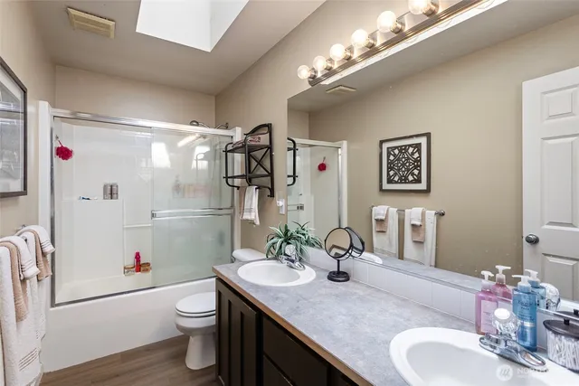 a bathroom with a granite countertop sink a toilet a mirror and shower