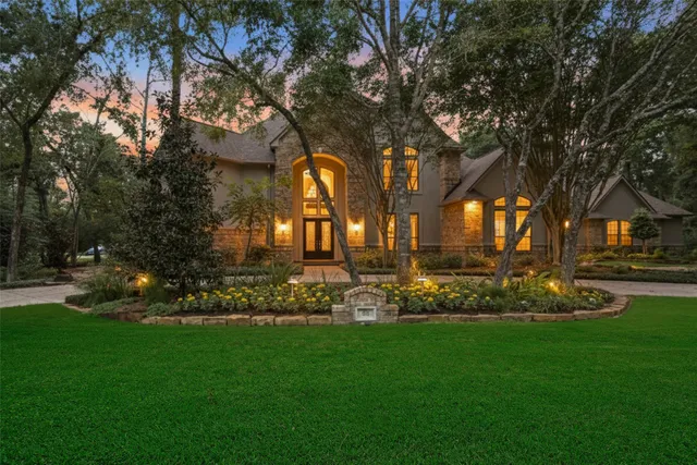 a view of a house with a big yard and potted plants and large trees