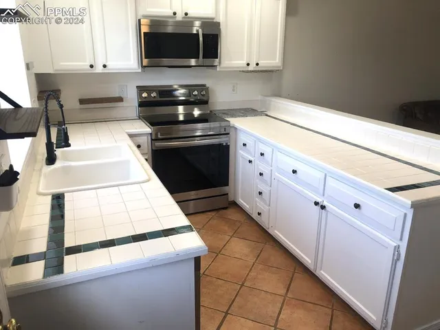 a kitchen with granite countertop white cabinets and black appliances