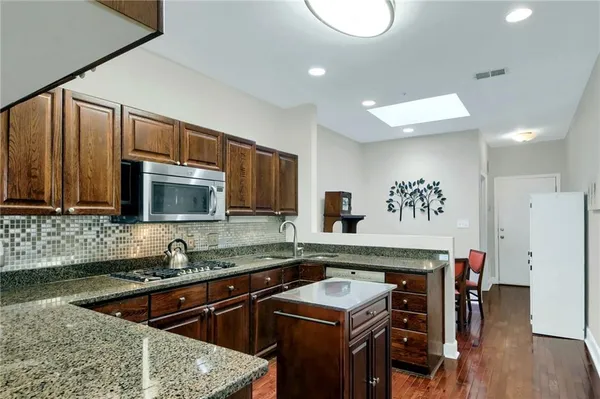 a kitchen with granite countertop white cabinets and stainless steel appliances