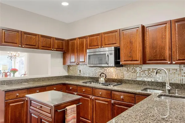 a kitchen with granite countertop a table chairs microwave and sink
