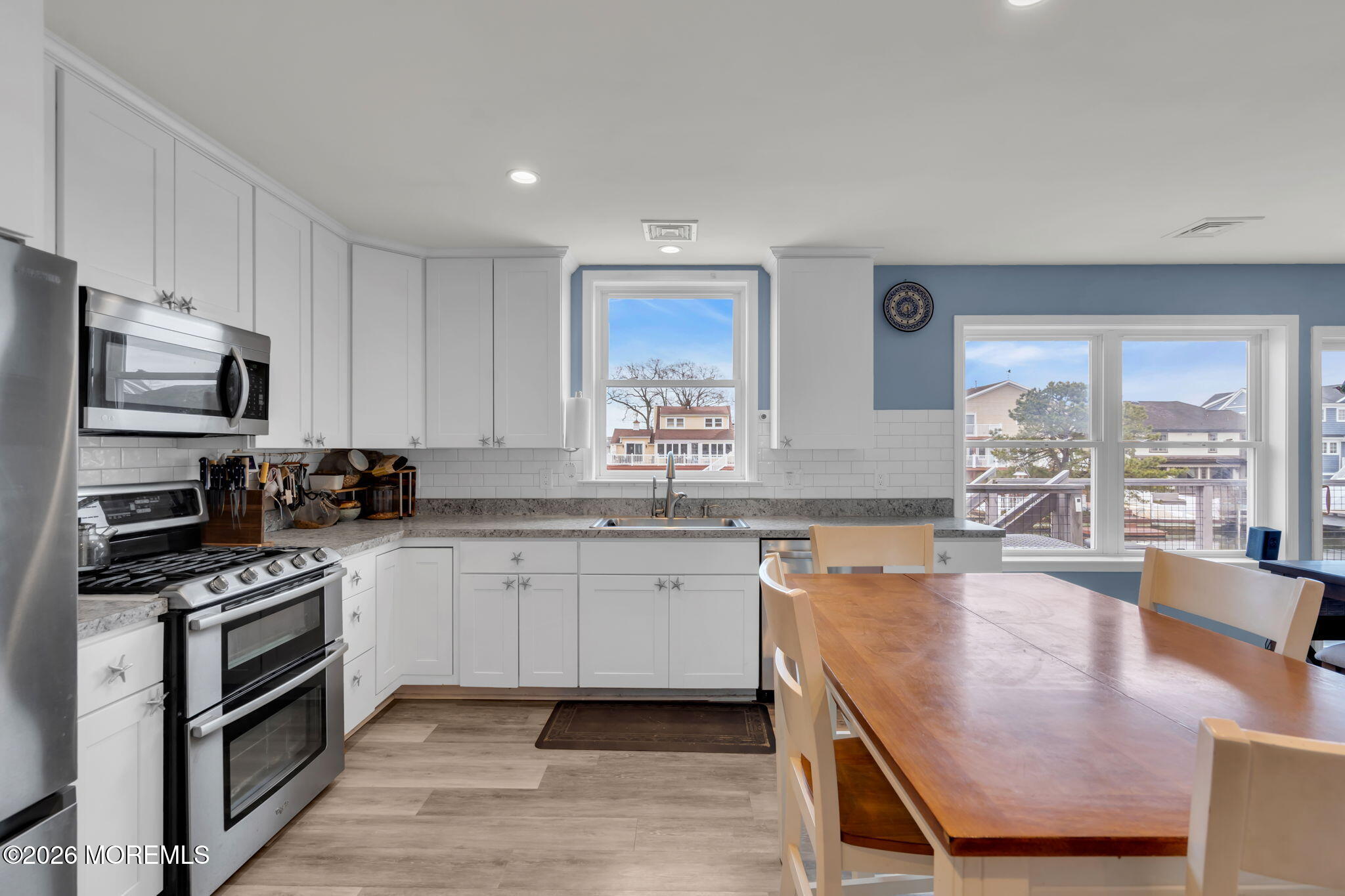 1622 Center Street Point Pleasant, NJ 08742 - Photo 4 of 42 a kitchen with stainless steel appliances granite countertop a stove top oven a sink dishwasher a dining table and chairs with wooden floor