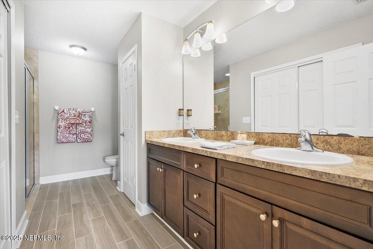 53347 Clear Lake Drive Callahan, FL 32011 - Photo 20 of 41 a spacious bathroom with a granite countertop sink a toilet a mirror and shower