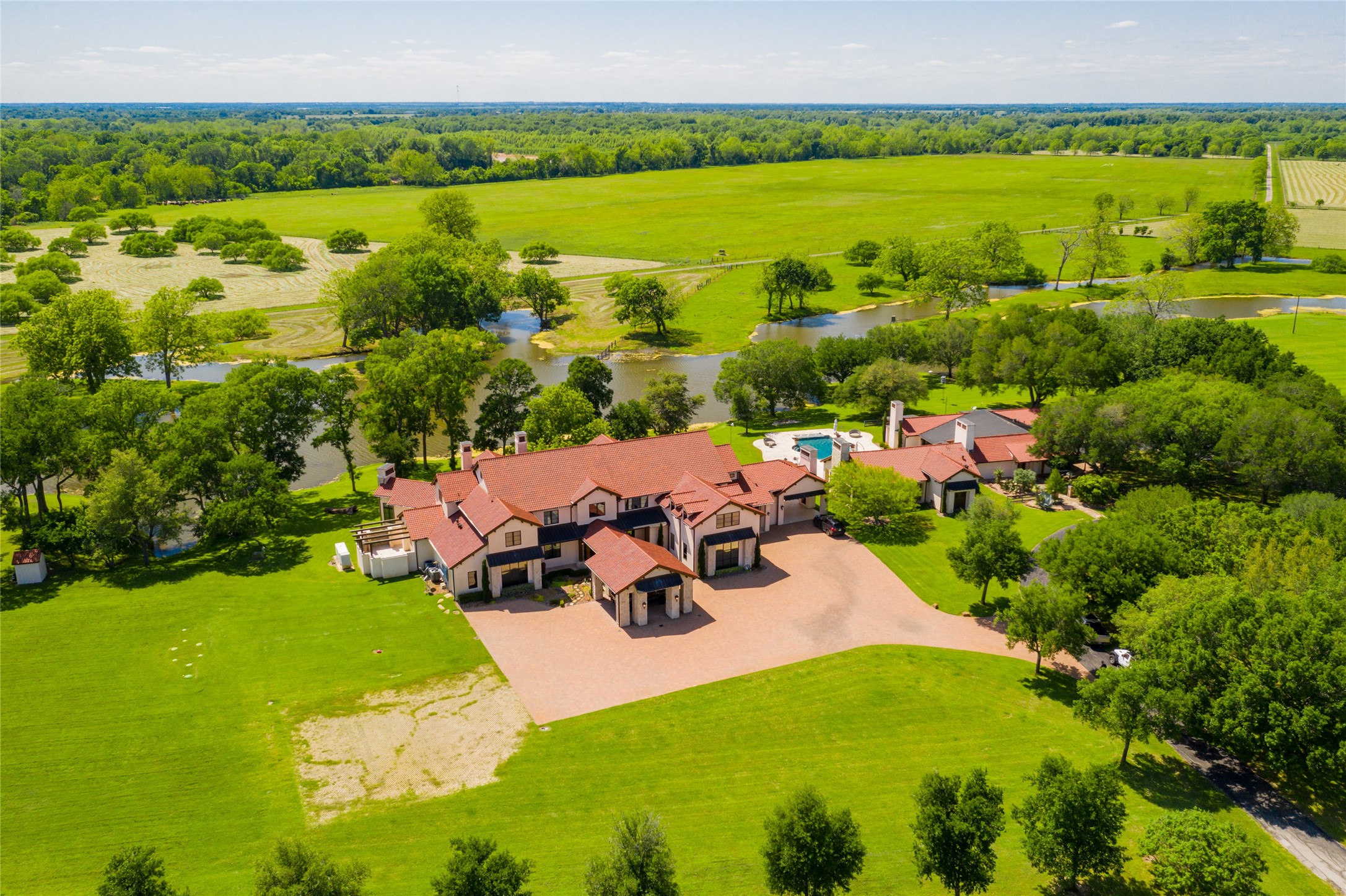 The incomparable Broad Oaks Ranch in Hempstead, includes 1,230+/- acres of 3.5 miles of Brazos River frontage with beaches, ponds, 12+/- acre stocked fishing lake, 5 water wells, improved/extensive open pastures and thick woods providing natural habitat for wildlife. Aerial view shows exquisitely appointed 4 bedroom/5 full bath/6 half baths main house, pool/hot tub/water features, remodeled 3 bedroom/3 bath guesthouse, barndominium, 8 stall horse barn and so much more!