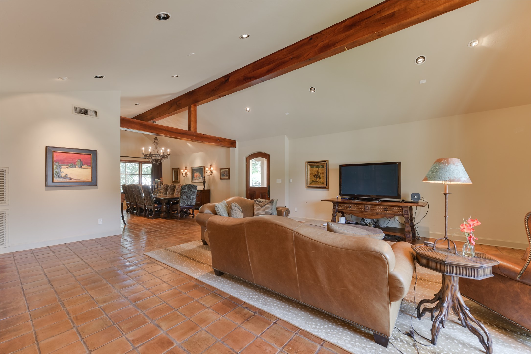 21729 Farm To Market 1887 Hempstead, TX 77445 - Photo 25 of 49 Upon entry through a stately wood/glass front door, the GUEST HOUSE'S LIVING ROOM (21 X 22) features saltillo tile flooring, pitched ceiling with exposed wood beams, gas log fireplace with metal screen/wood mantle, painted walls, mullioned windows with drapery, recessed lighting/art lighting, built-in shelving with cabinets below. Notice the DINING ROOM beyond (19 X 14) with its metal/glass chandelier.