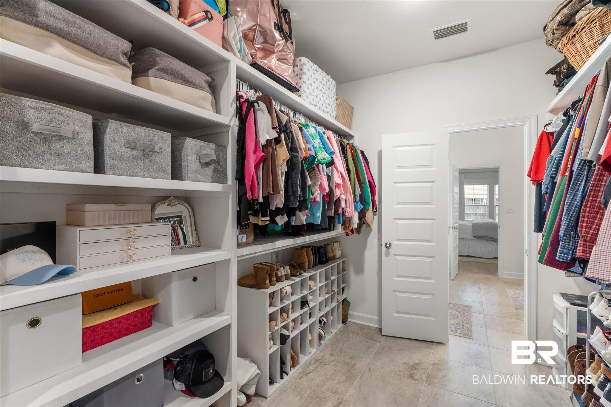9074 Moses Way Theodore, AL 36582 - Photo 27 of 52 Walk-in closet featuring built-in shelving, clothing racks, shoe storage, and light-toned tile flooring