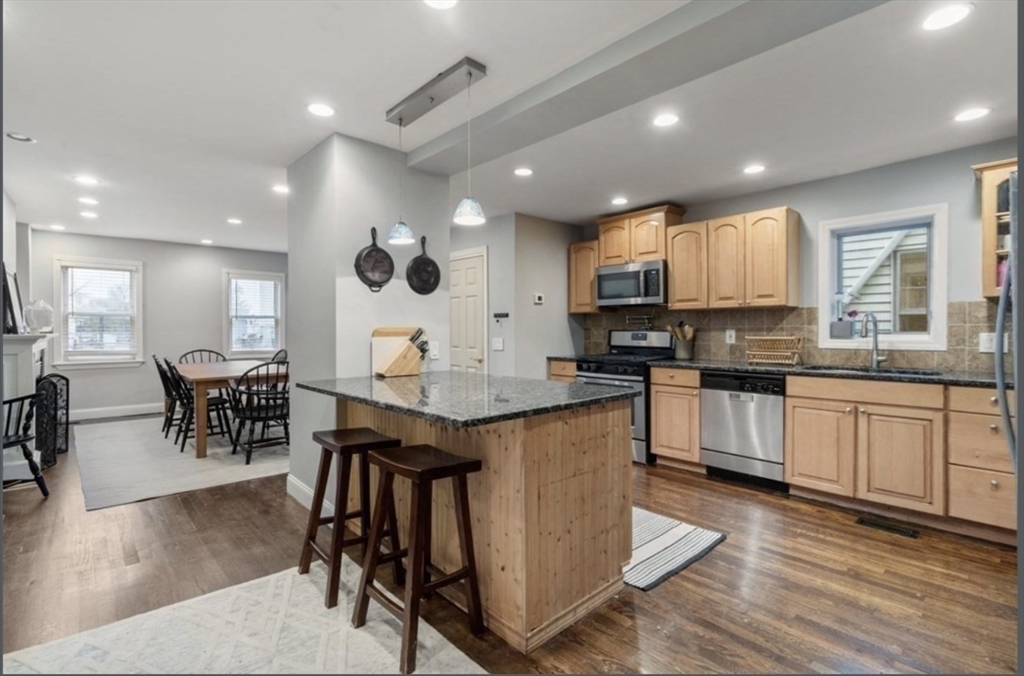a kitchen with stainless steel appliances granite countertop wooden cabinets a dining table and chairs