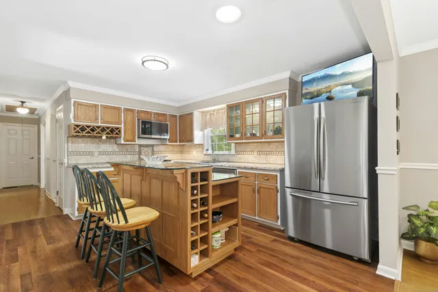 a kitchen with stainless steel appliances a stove a sink dishwasher a refrigerator with a dining table and chairs