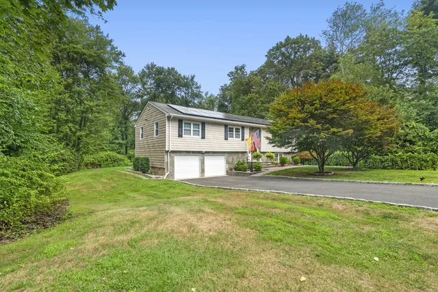 a view of a house with a big yard and large trees
