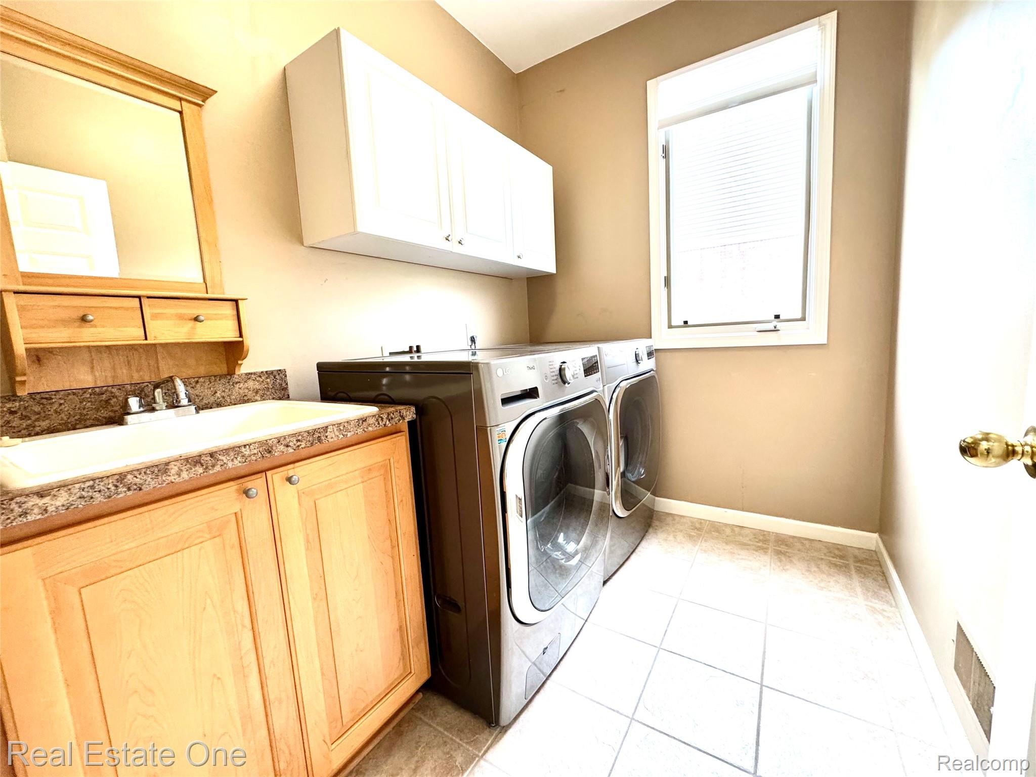 1215 Letica Drive Rochester, MI 48307 - Photo 12 of 43 Laundry room with separate washer and dryer, cabinet space, and light tile patterned floors