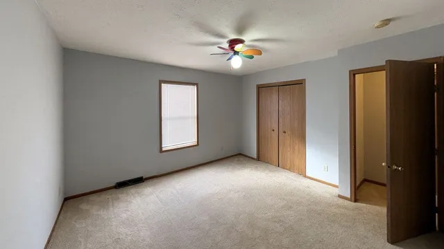 a view of an empty room with window and chandelier fan