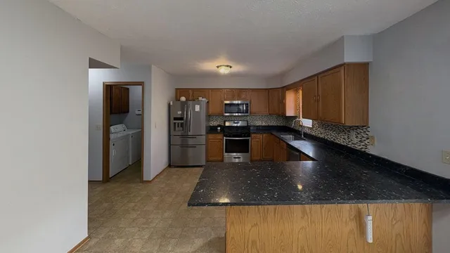 a kitchen with stainless steel appliances granite countertop a sink a stove and a refrigerator
