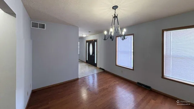 a view of a hallway with wooden floor and chandelier