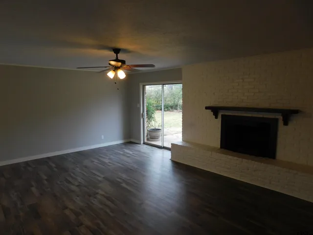an empty room with wooden floor fireplace and windows