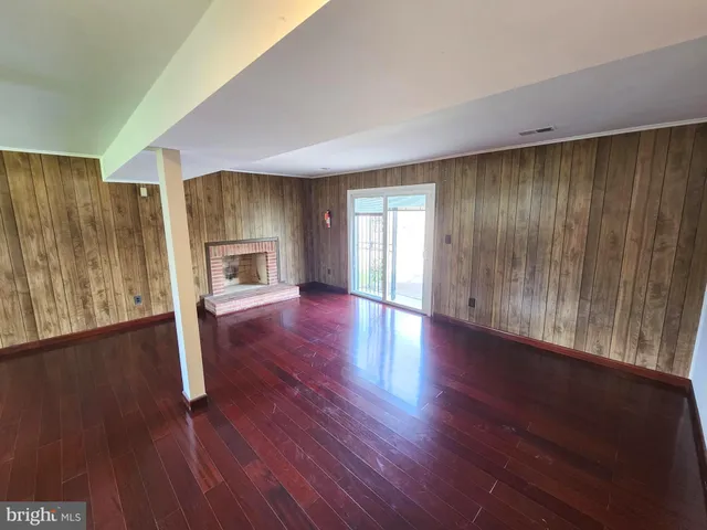 an empty room with wooden floor fireplace and windows
