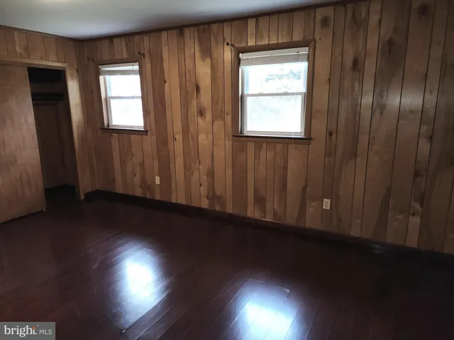 an empty room with wooden floor and windows with curtains