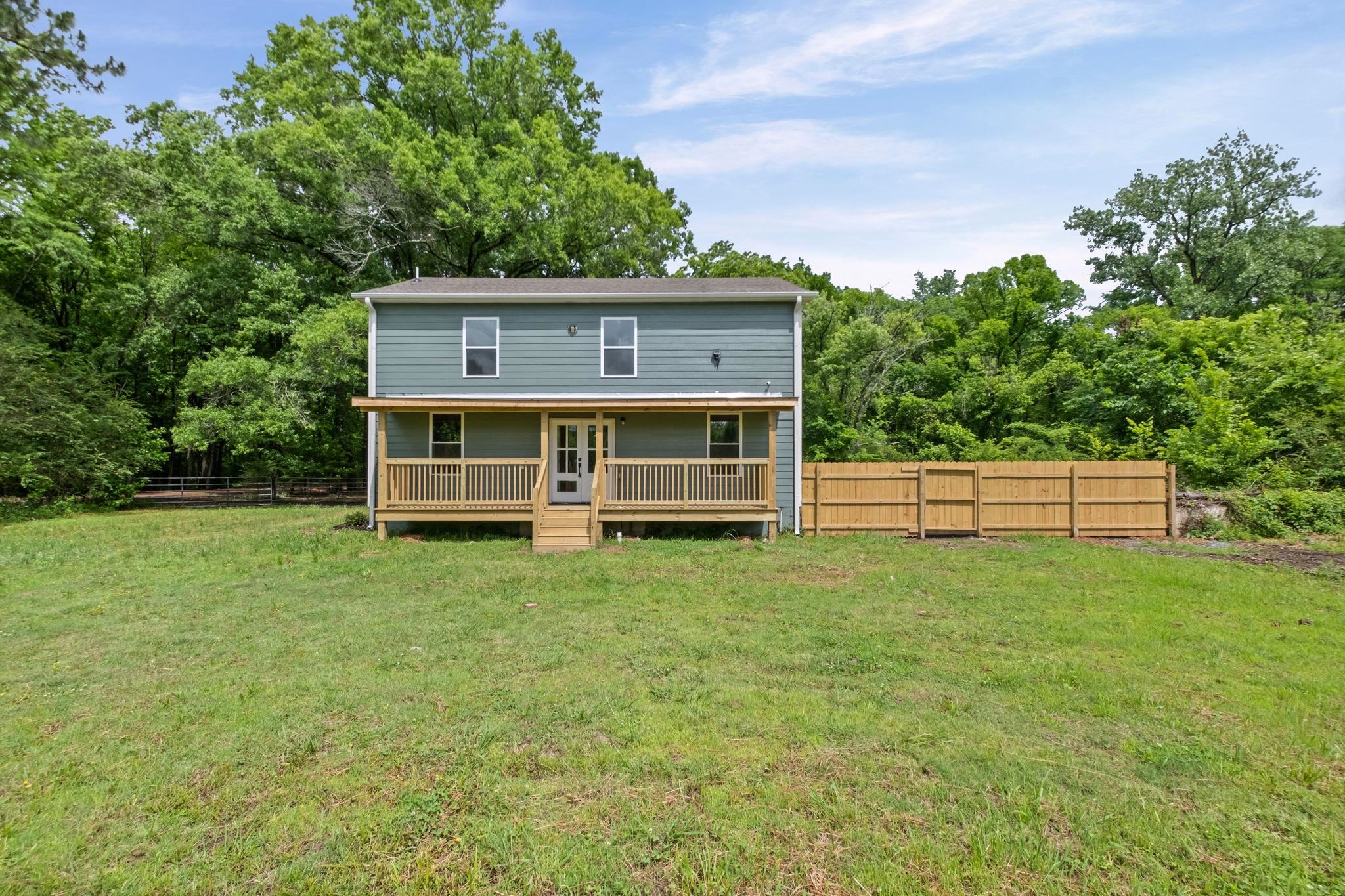 5843 Stewart Road Lakeland, TN 38002 - Photo 2 of 26 Two-story home with a light blue siding exterior, featuring a full-width covered porch with a wood railing and steps