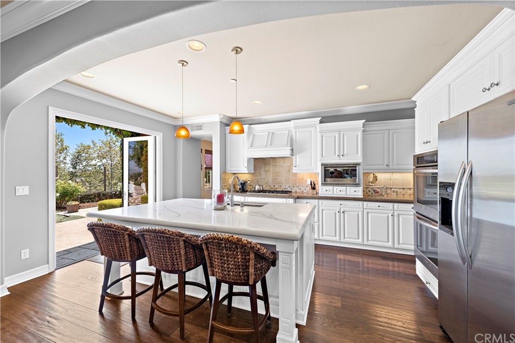 a kitchen with stainless steel appliances granite countertop a table chairs refrigerator and wooden cabinets