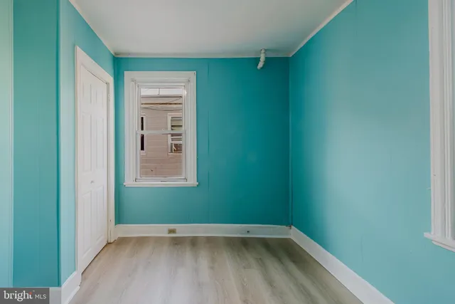 a view of an empty room with wooden floor and closet