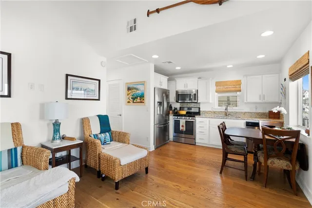 a living room with stainless steel appliances kitchen island granite countertop furniture and a wooden floor