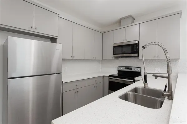 a kitchen with stainless steel appliances a refrigerator sink and microwave