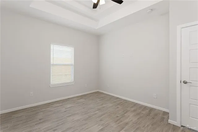 an empty room with wooden floor cabinet and windows