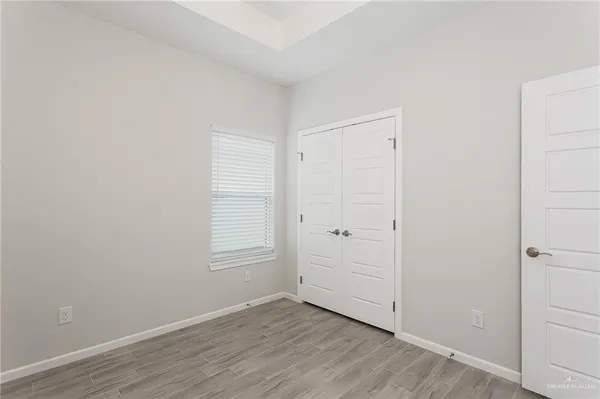 a view of an empty room with wooden floor and closet