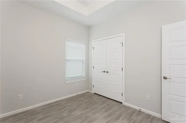 a view of an empty room with wooden floor and closet