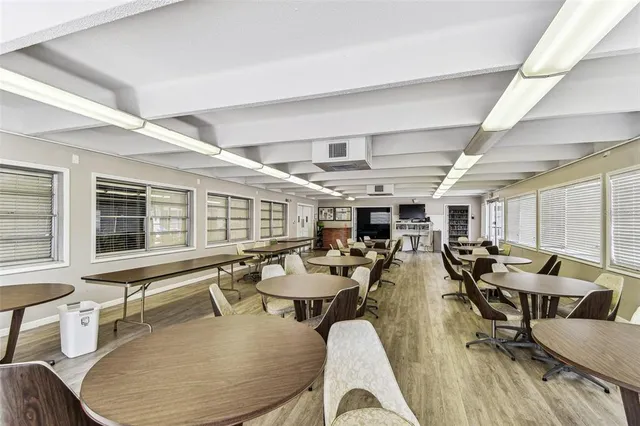 a room with lots of tables a large window and chairs