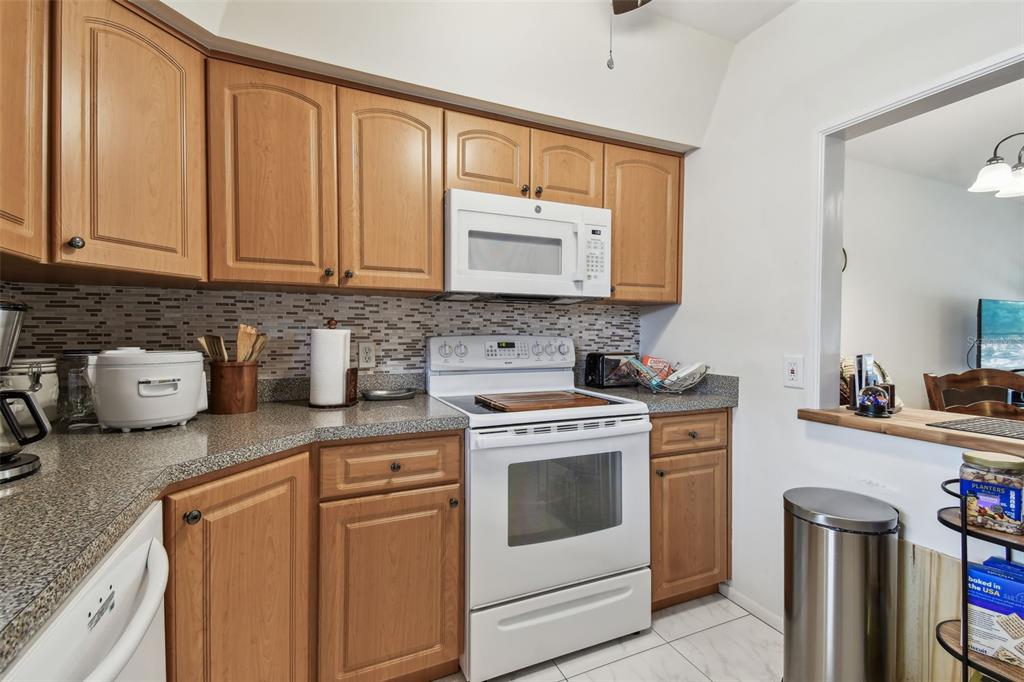 9945 47th Avenue North, Unit 208 St. Petersburg, FL 33708 - Photo 5 of 38 a kitchen with stainless steel appliances granite countertop a stove a sink and a microwave