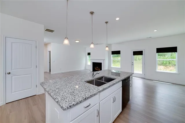 a kitchen with stainless steel appliances granite countertop a sink a stove and a wooden floor