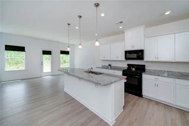 a large kitchen with stainless steel appliances granite countertop a stove a sink and a wooden floors