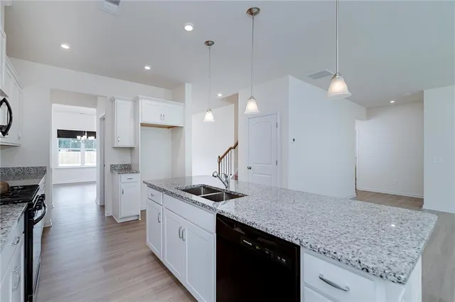 a kitchen with stainless steel appliances granite countertop a sink a stove and a wooden floors