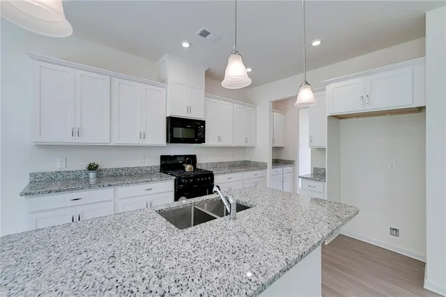 a kitchen with granite countertop a sink a counter space appliances and cabinets