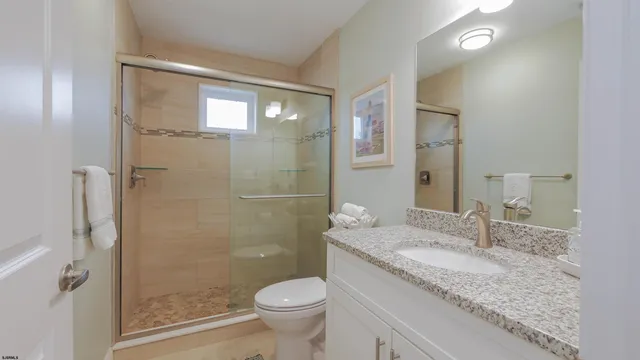 a bathroom with a granite countertop sink a toilet and shower