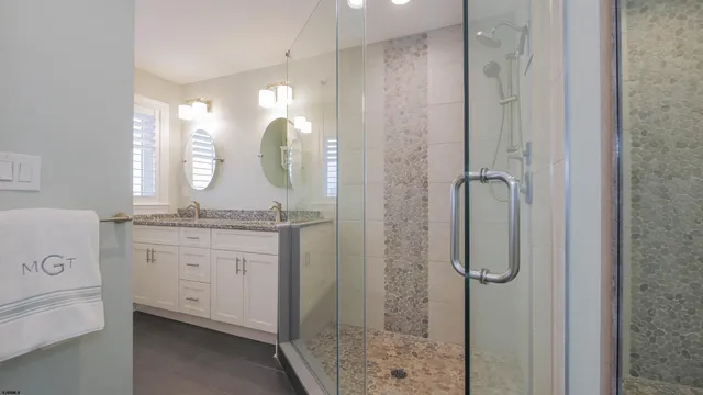 a bathroom with a granite countertop sink a mirror and a shower