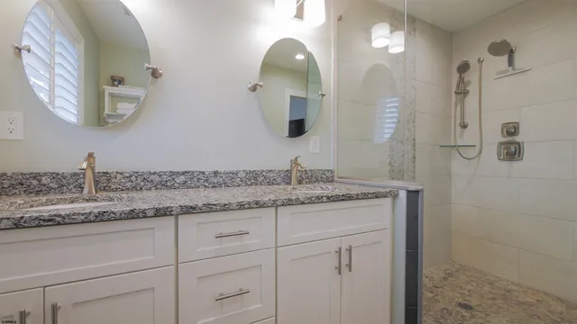 a bathroom with a granite countertop sink a mirror and shower