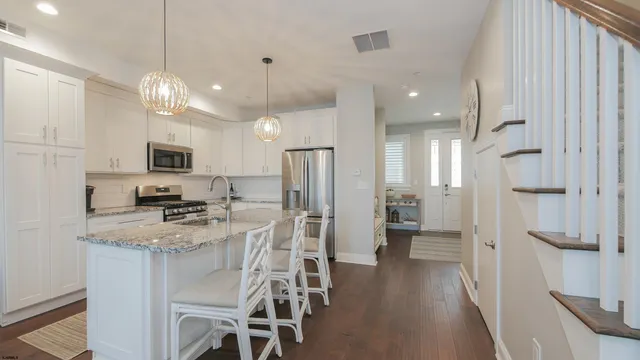 a kitchen with stainless steel appliances kitchen island granite countertop a refrigerator a stove a microwave oven a sink with island and chairs