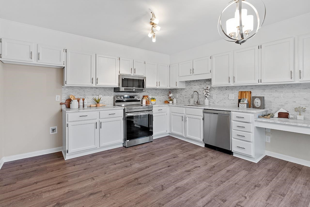 5516 Middleton Road Durham, NC 27713 - Photo 3 of 35 a kitchen with cabinets wooden floor and stainless steel appliances