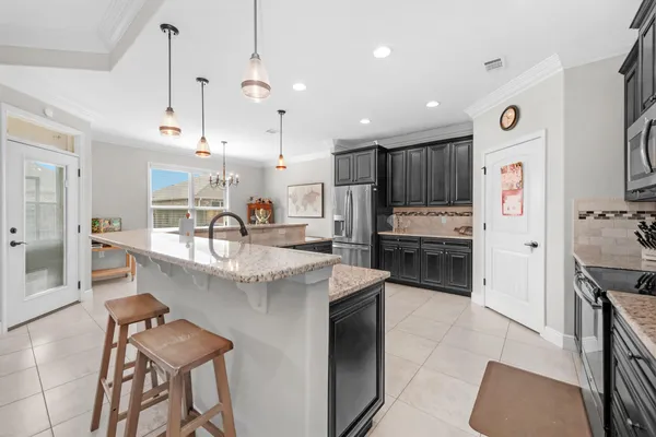 a kitchen with stainless steel appliances kitchen island granite countertop a sink and a refrigerator
