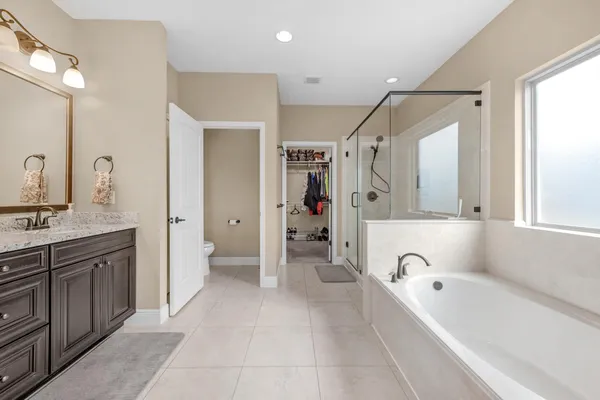 a bathroom with a tub a sink a mirror and a shower