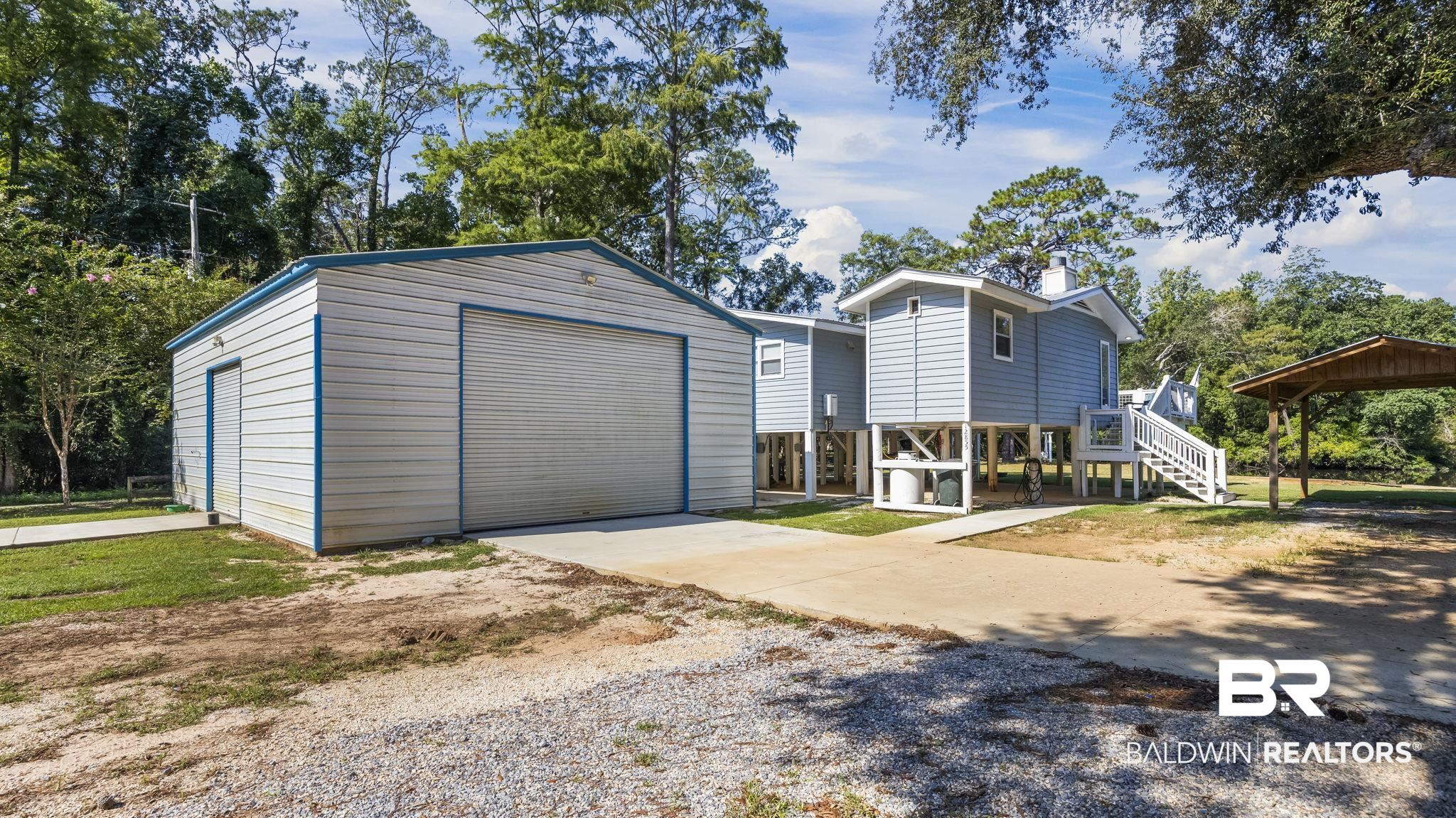 12855 Woodhaven Dairy Road West Silverhill, AL 36576 - Photo 7 of 27 View of front of property featuring driveway, an outbuilding, stairs, and a garage
