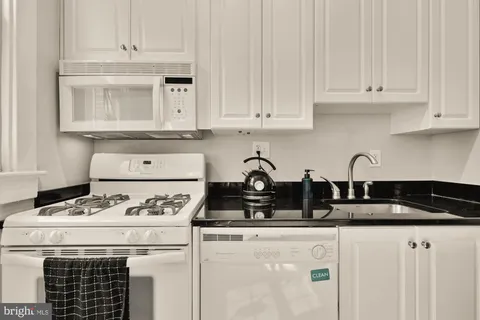 a kitchen with appliances a refrigerator and white cabinets