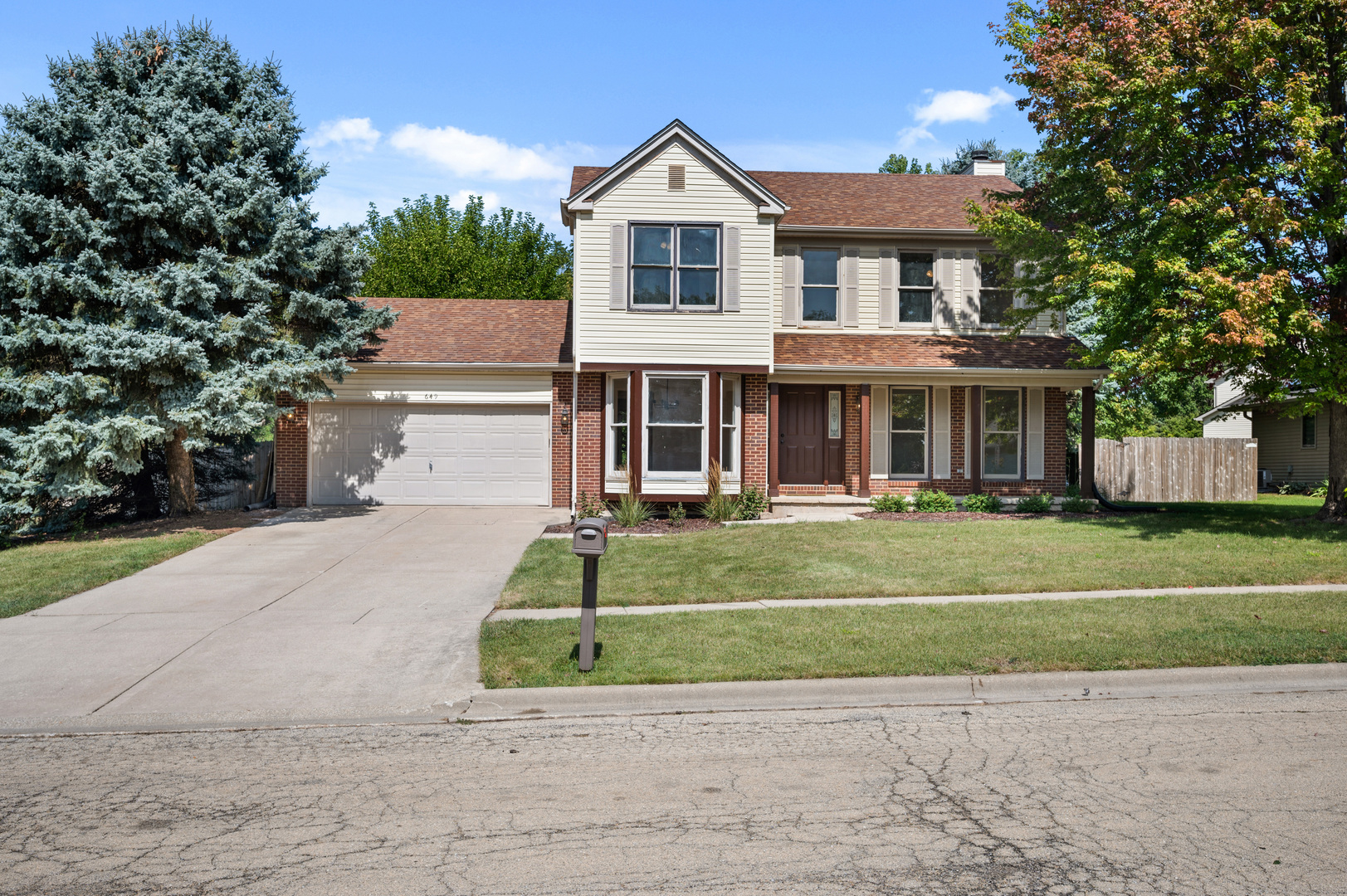 a front view of a house with a yard and trees