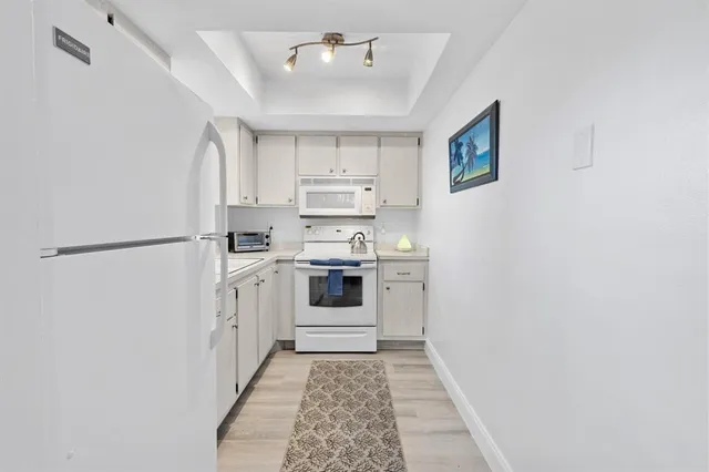 a kitchen with white cabinets and white appliances