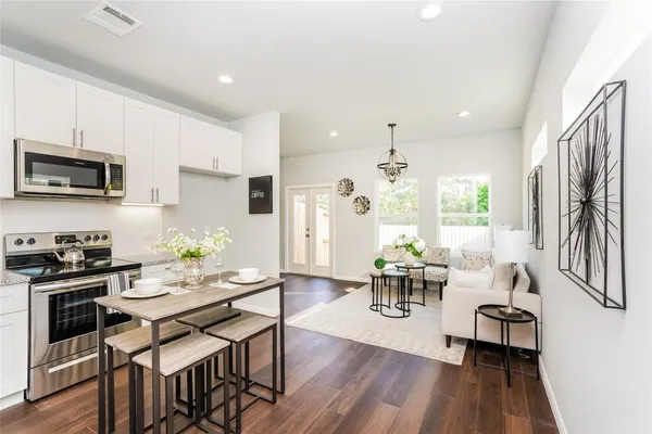 a kitchen with stainless steel appliances a dining table chairs stove refrigerator and cabinets