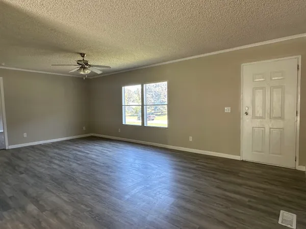 an empty room with wooden floor closet and windows