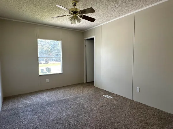 an empty room with windows and fan