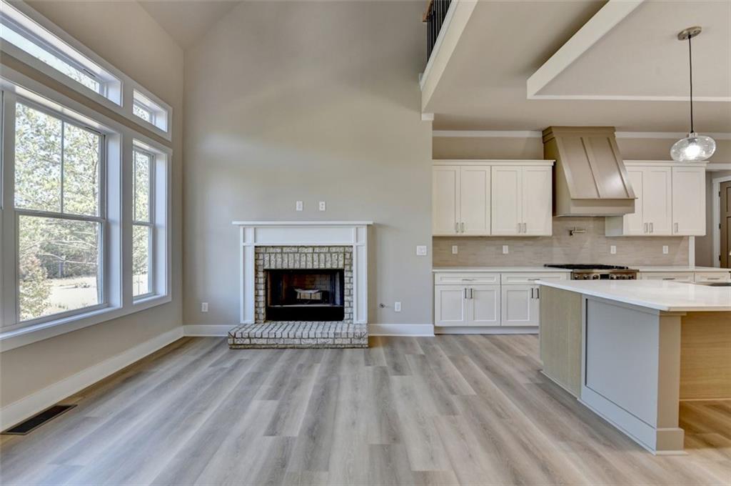 2881 Traditions Way Jefferson, GA 30549 - Photo 15 of 59 a open kitchen with granite countertop a stove top oven a sink dishwasher and a fireplace with wooden floor